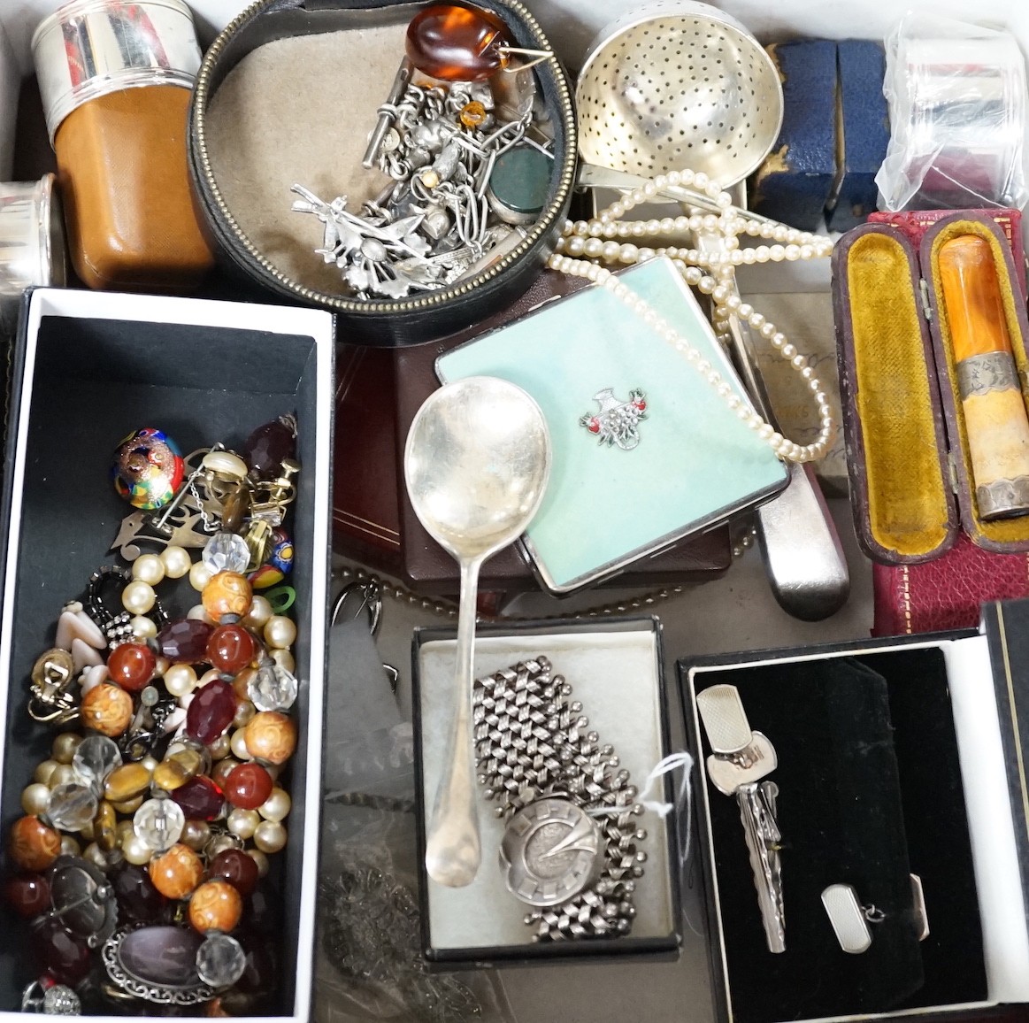 A collection of assorted jewellery including costume, silver and enamel flower head brooch, silver mounted amber cigarette holder, plated flatware, necklaces, commemorative coin, Victorian silver locket, white metal brac